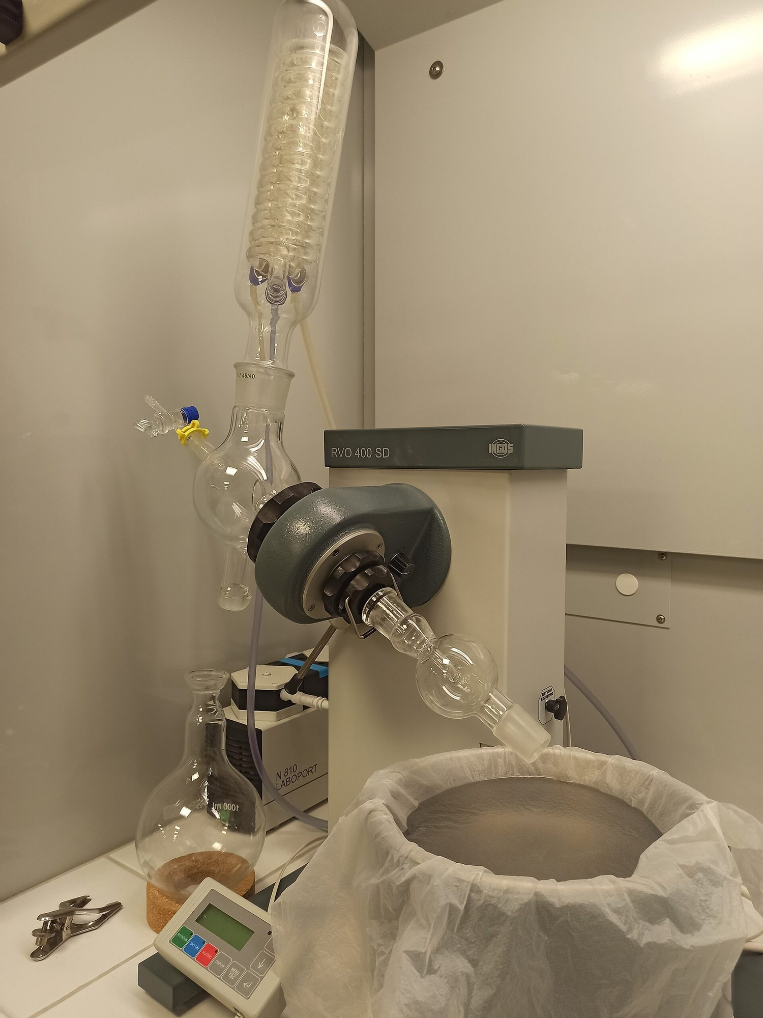 Un evaporador rotatorio: un matraz redondo con solución girando en un baño de agua caliente, con el vapor del solvente condensándose en un matraz receptor separado