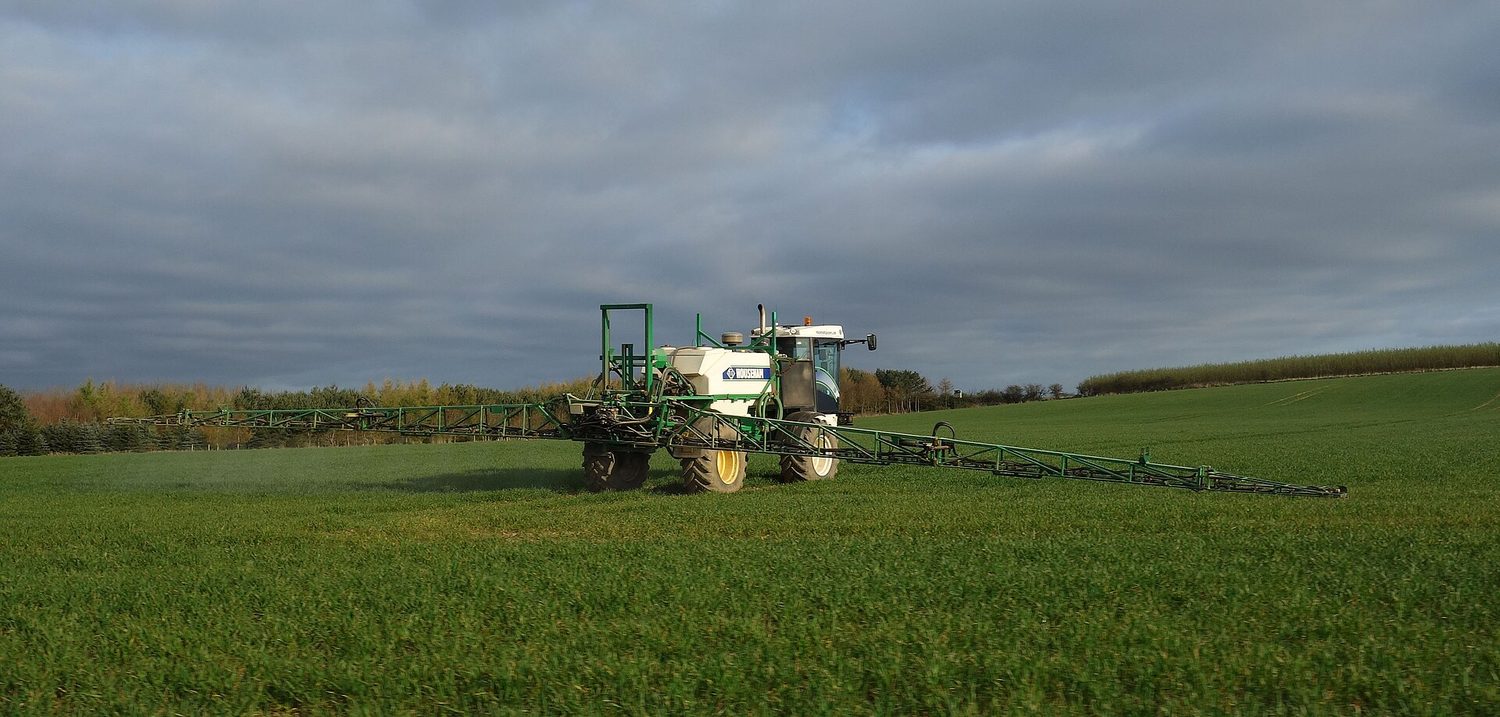 A tractor spraying a crop in a field
