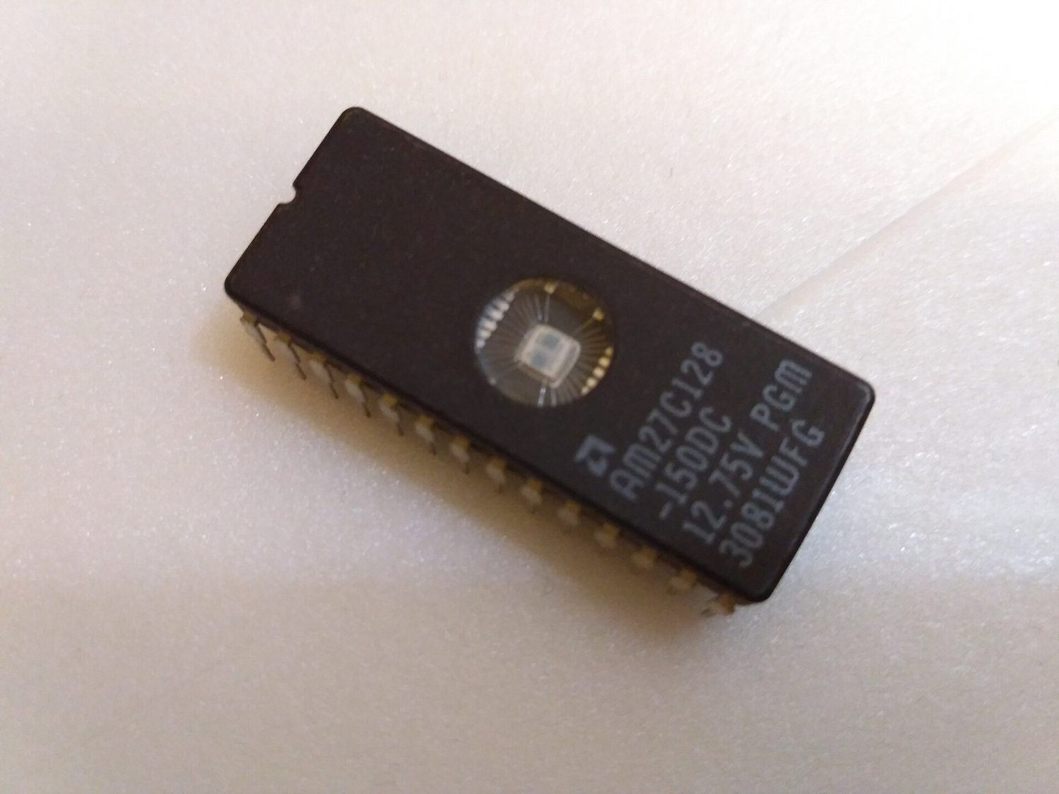 A black EPROM chip with a circular quartz window exposing its silicon die
