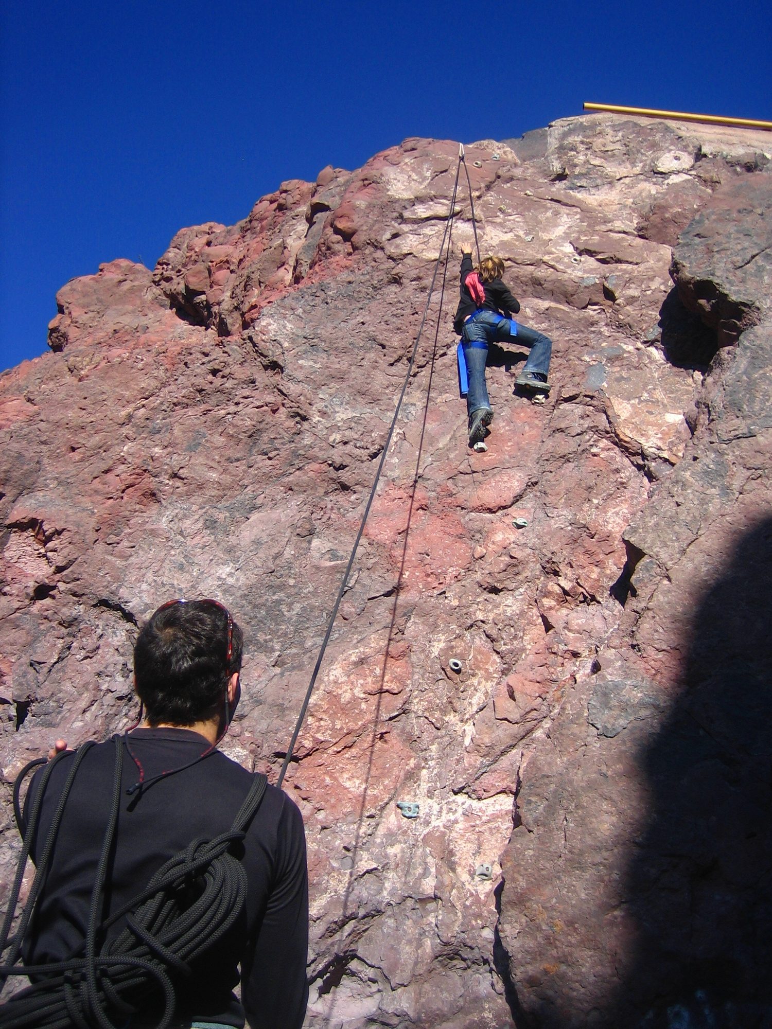 A climber hanging from a rope on a steep sea cliff, held away from the rock face