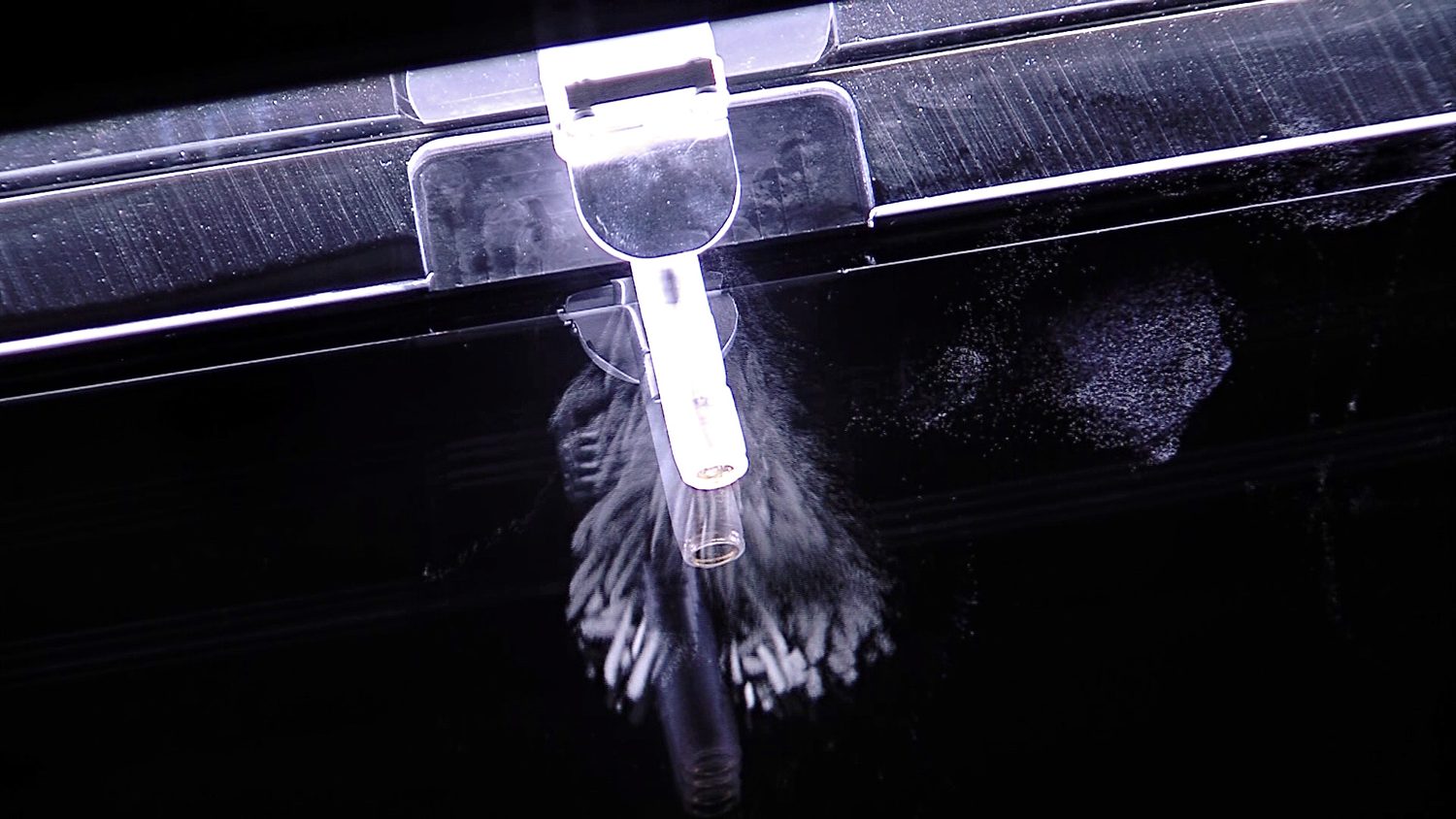 A cloud chamber photograph: short, straight, thick white trails of vapour fan out from a small radioactive source, marking the paths of alpha particles through the cold gas