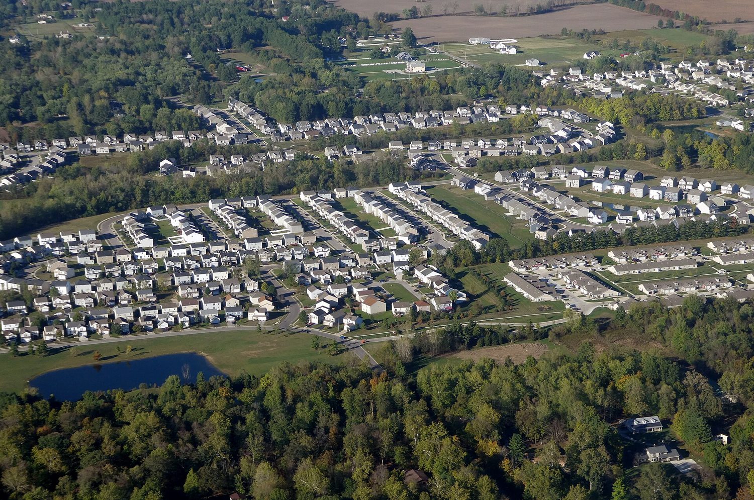 An aerial view of low-density single-family houses spreading out to the horizon over former fields