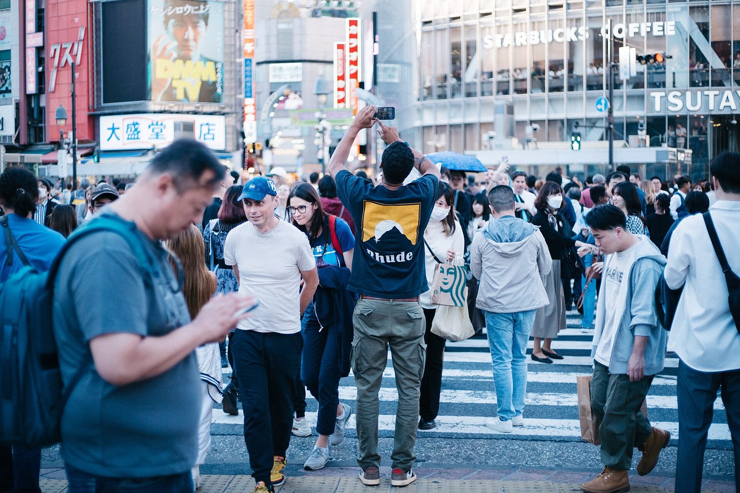 Hundreds of people crossing a wide street intersection at once, filling every part of it