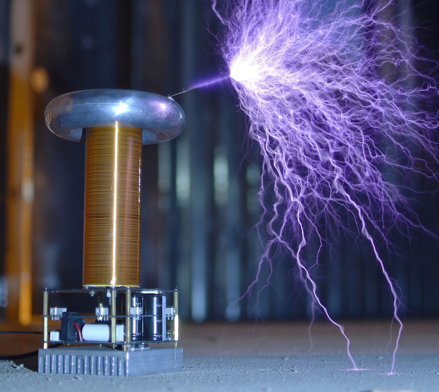 A Tesla coil topped by a metal ring, throwing long purple sparks out into the air