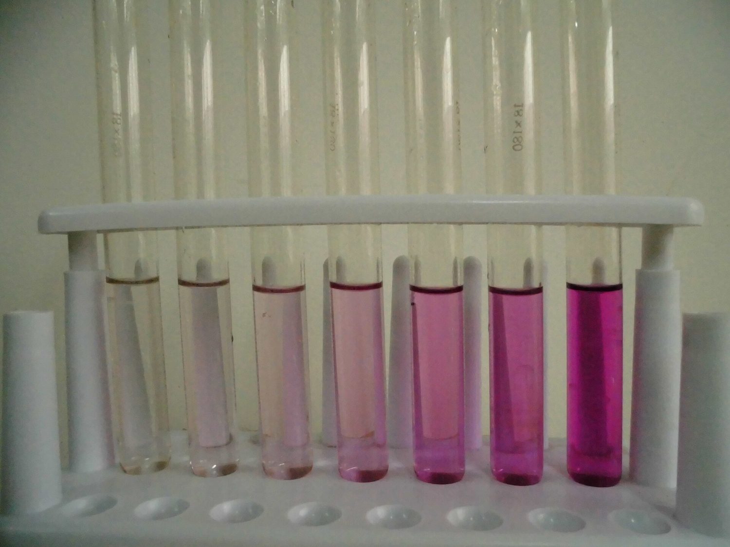 A rack of test tubes of potassium manganate(VII), going from deep purple on the right to colourless on the left as it gets more dilute