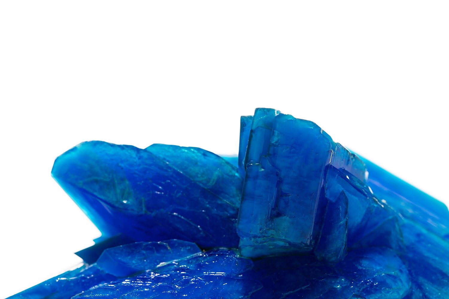 Bright blue geometric crystals of copper(II) sulfate against a white background