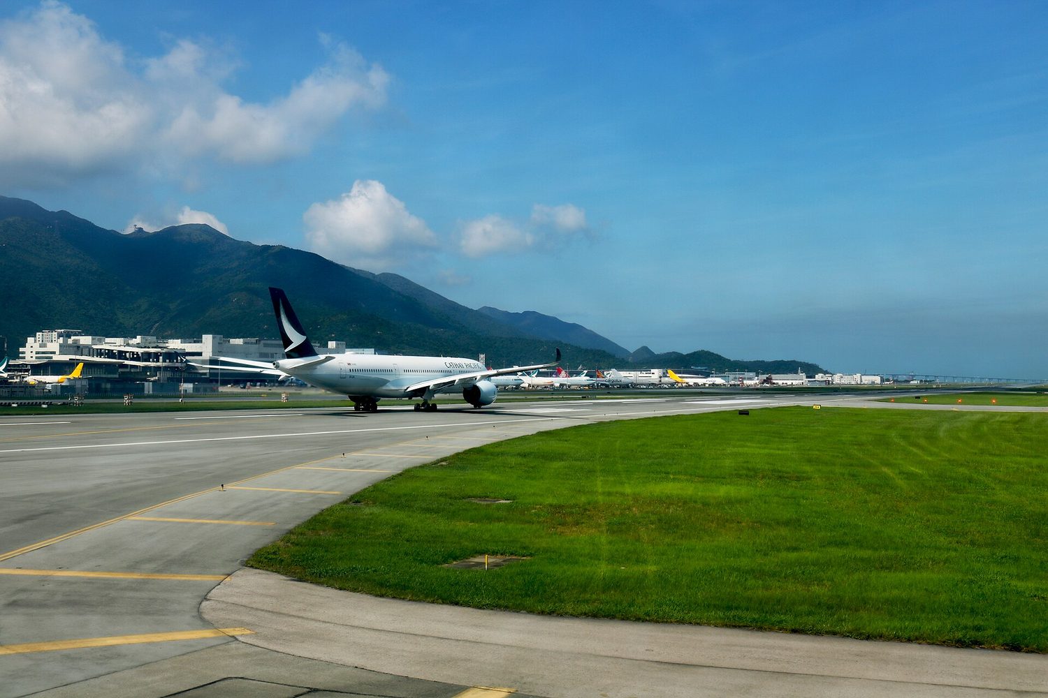A large passenger jet on an airport runway with hills behind