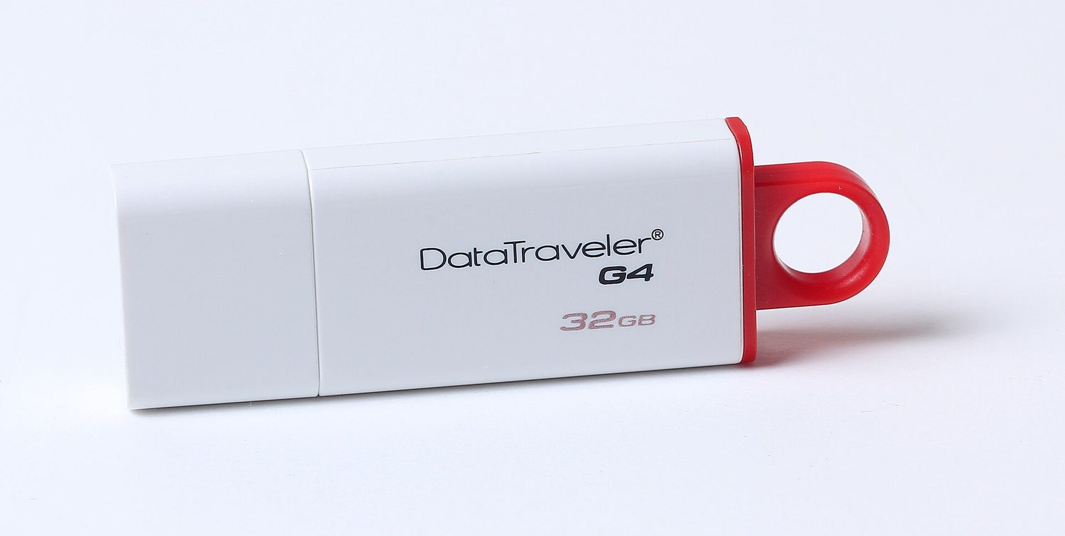 A small white USB stick with a red cap loop, labelled 32 GB