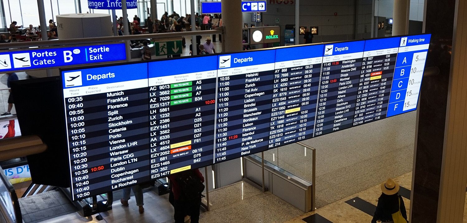 Um grande painel de partidas de aeroporto listando muitos horários, destinos e portões