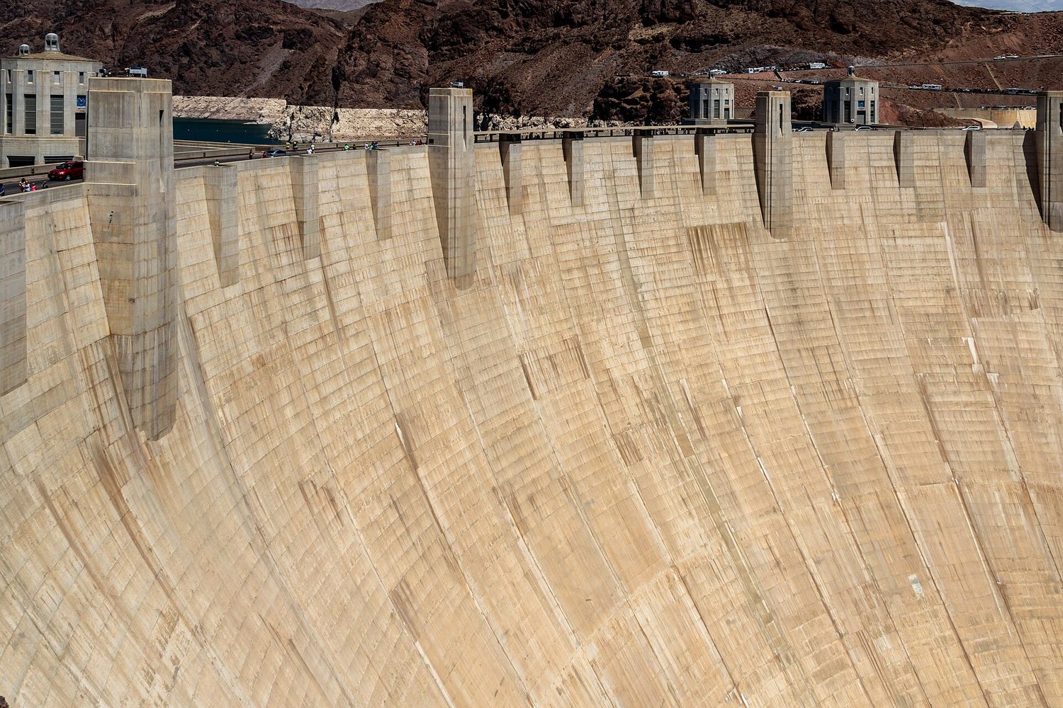 The huge curved concrete wall of the Hoover Dam holding back a reservoir