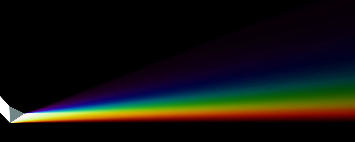 A narrow beam of white light entering a glass prism and fanning out into a bright band of rainbow colours on a black background