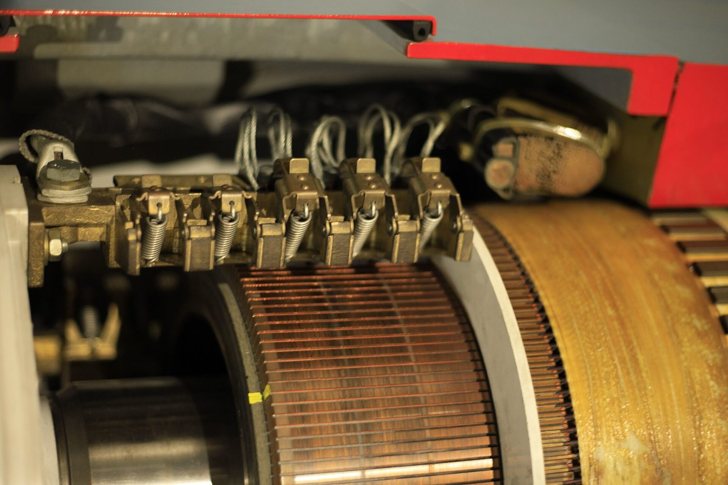 Close-up of carbon brushes on springs pressing against the copper bars of a d.c. machine commutator