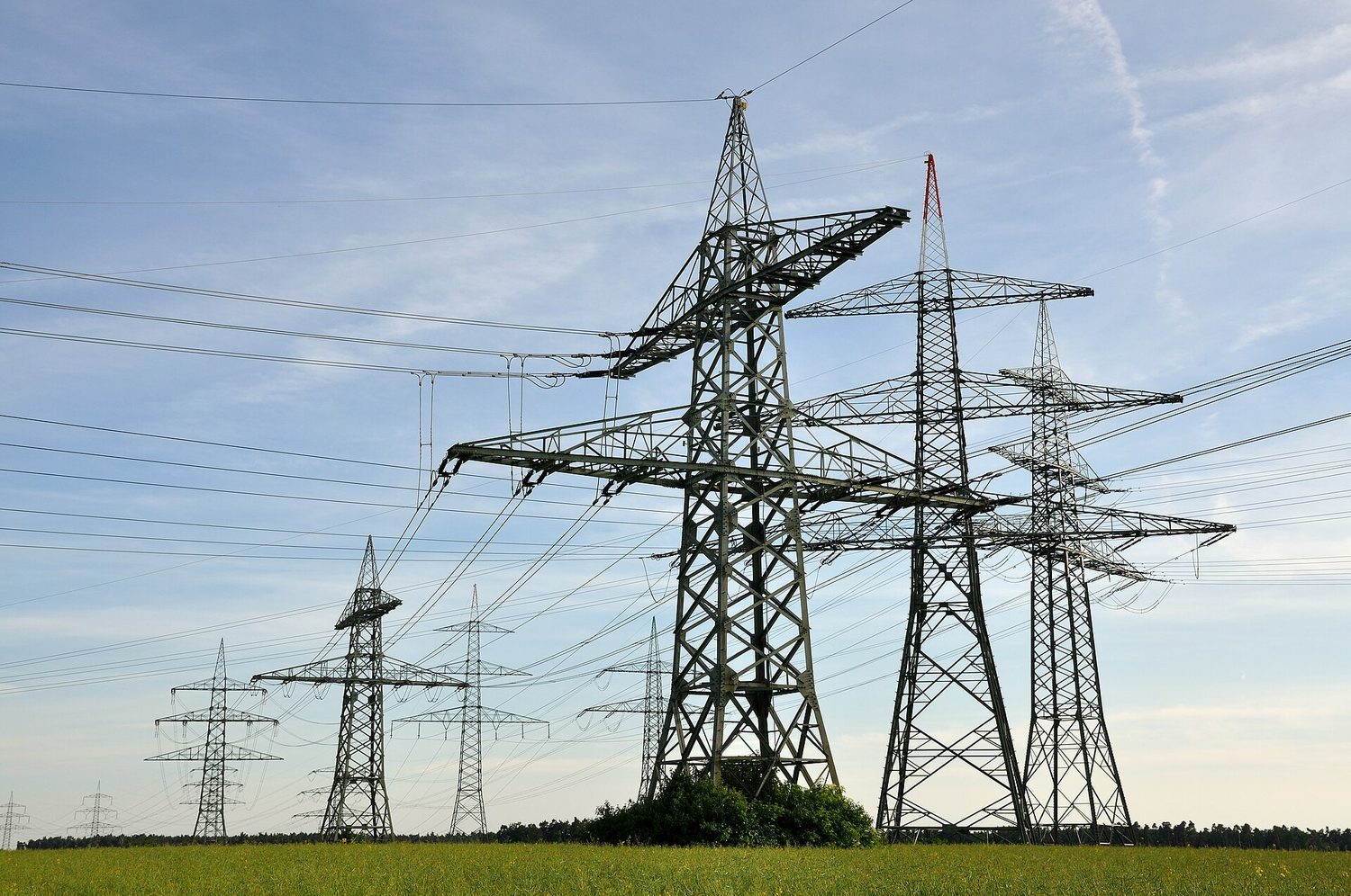 Steel lattice pylons carrying many cables across open countryside